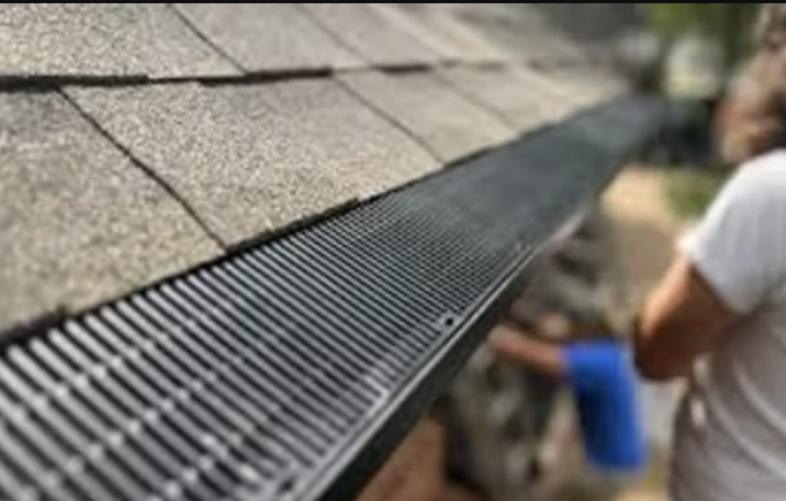A person is standing next to a gutter on a roof.