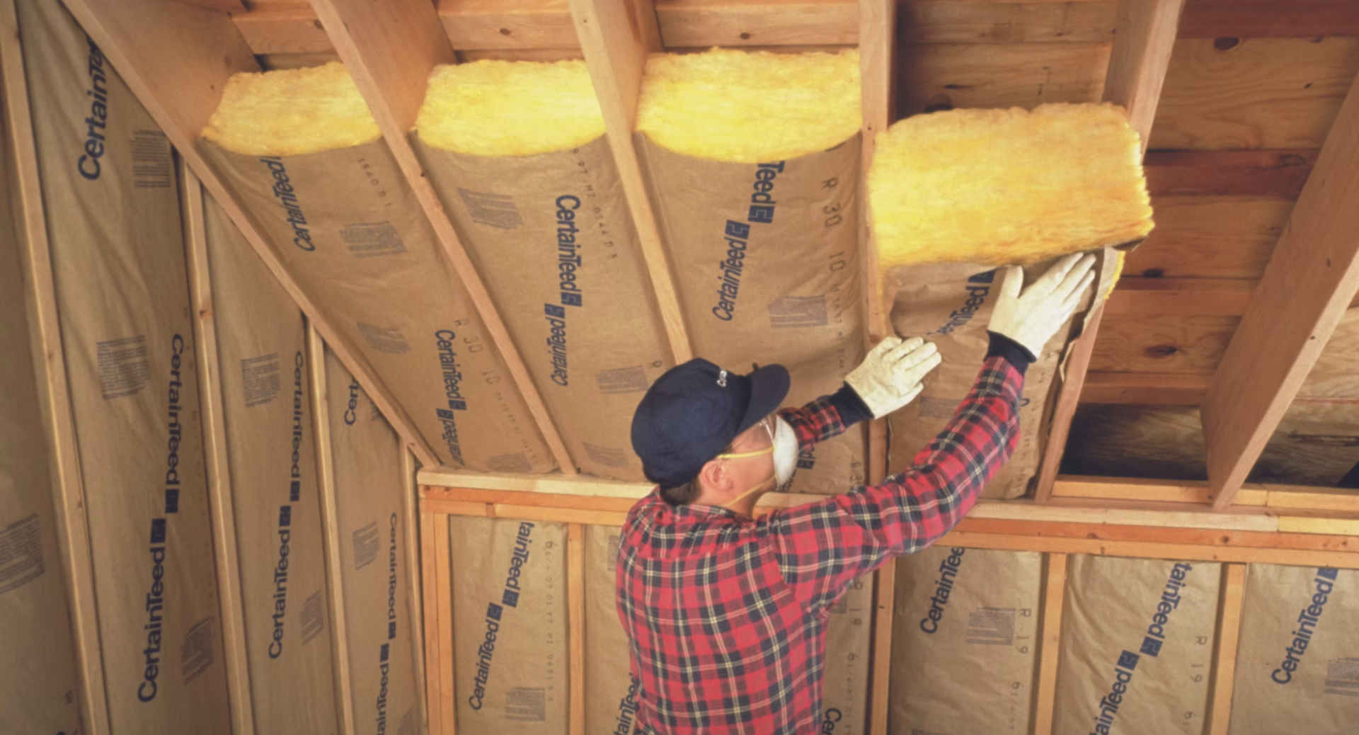 A man is installing insulation on the ceiling of a house.