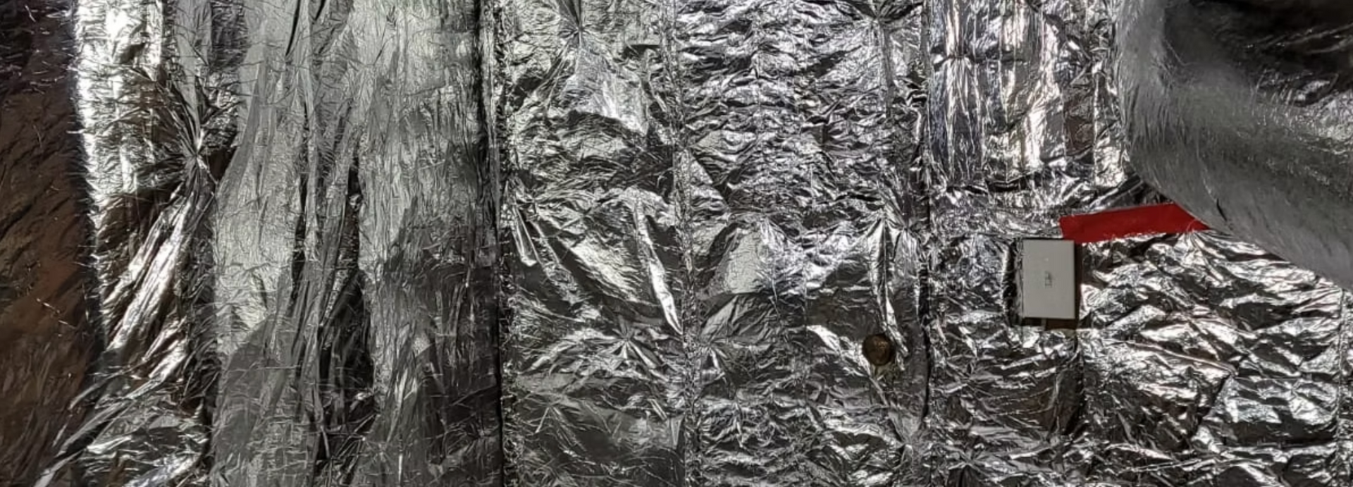 A small house is sitting next to a waterfall covered in aluminum foil.
