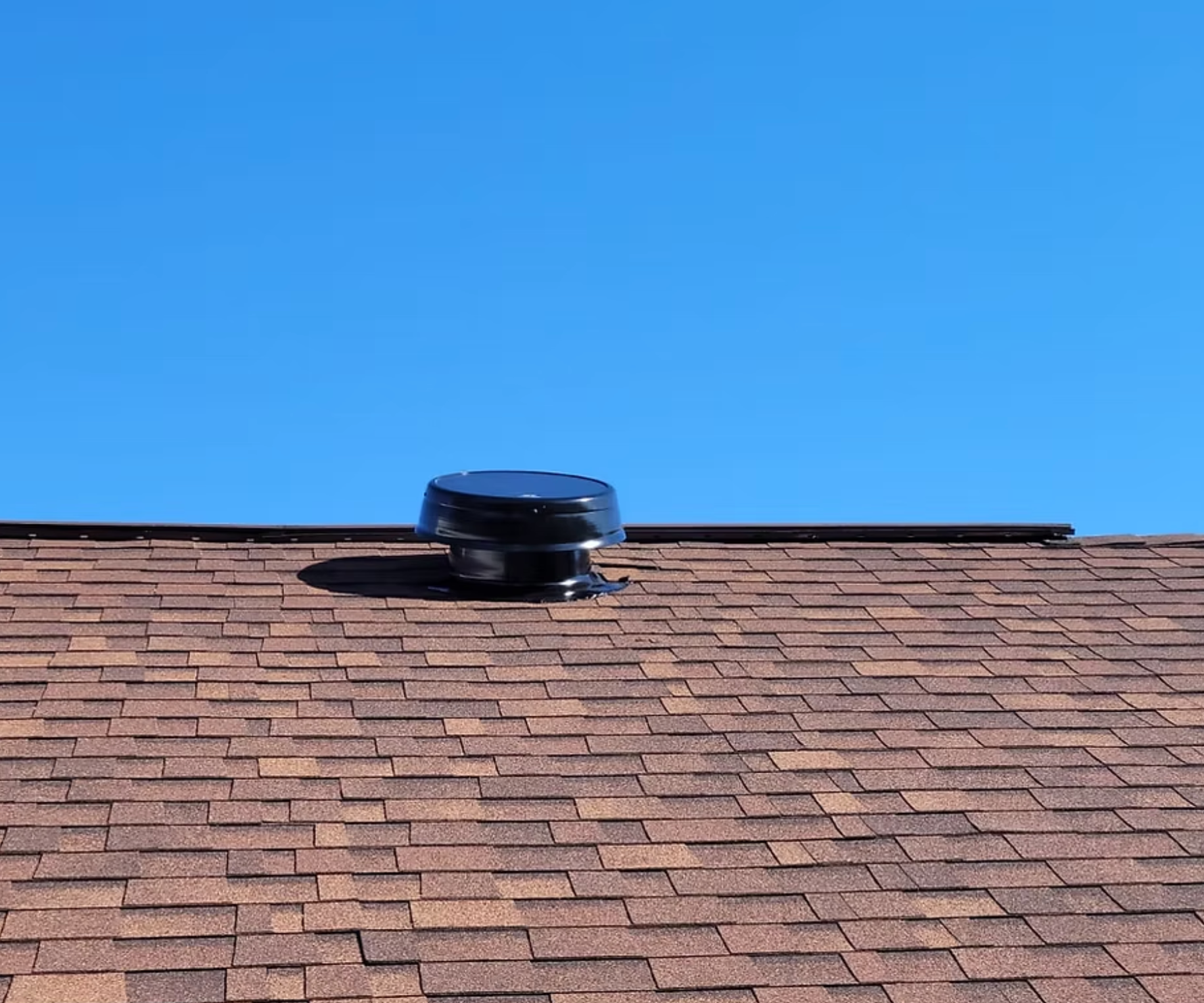A roof with a vent on it and a blue sky in the background