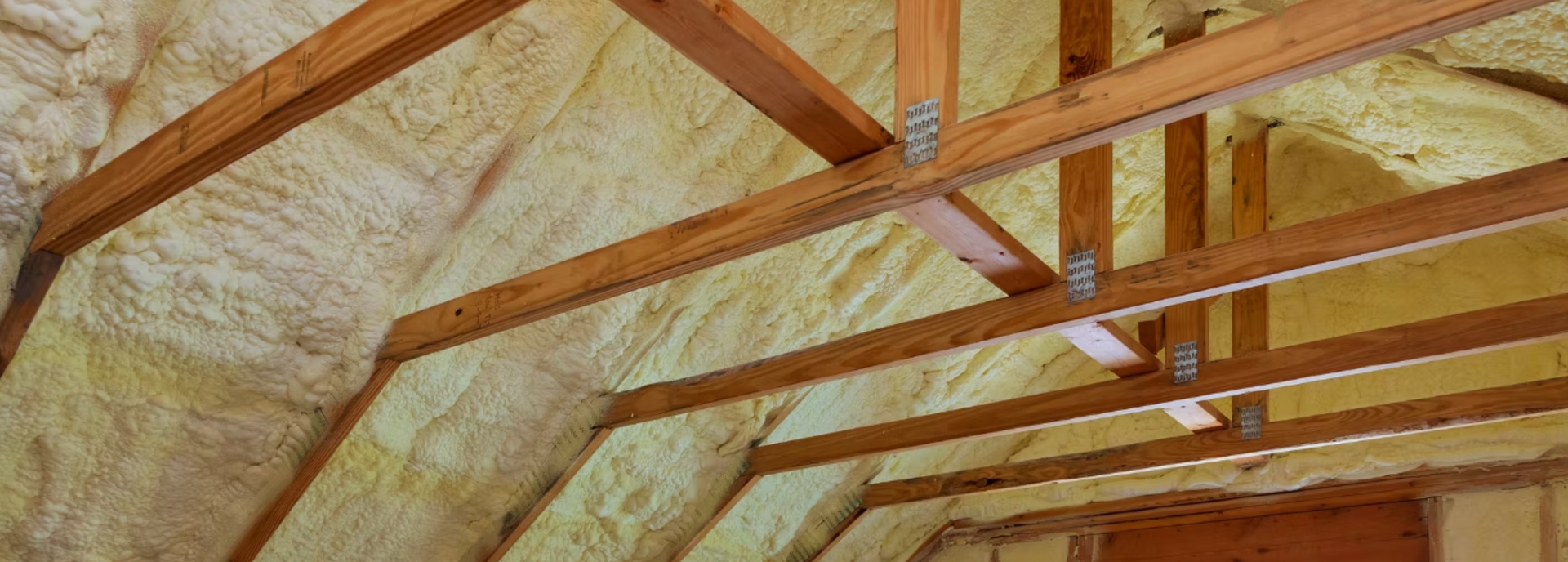 The ceiling of a house with wooden beams and foam insulation.