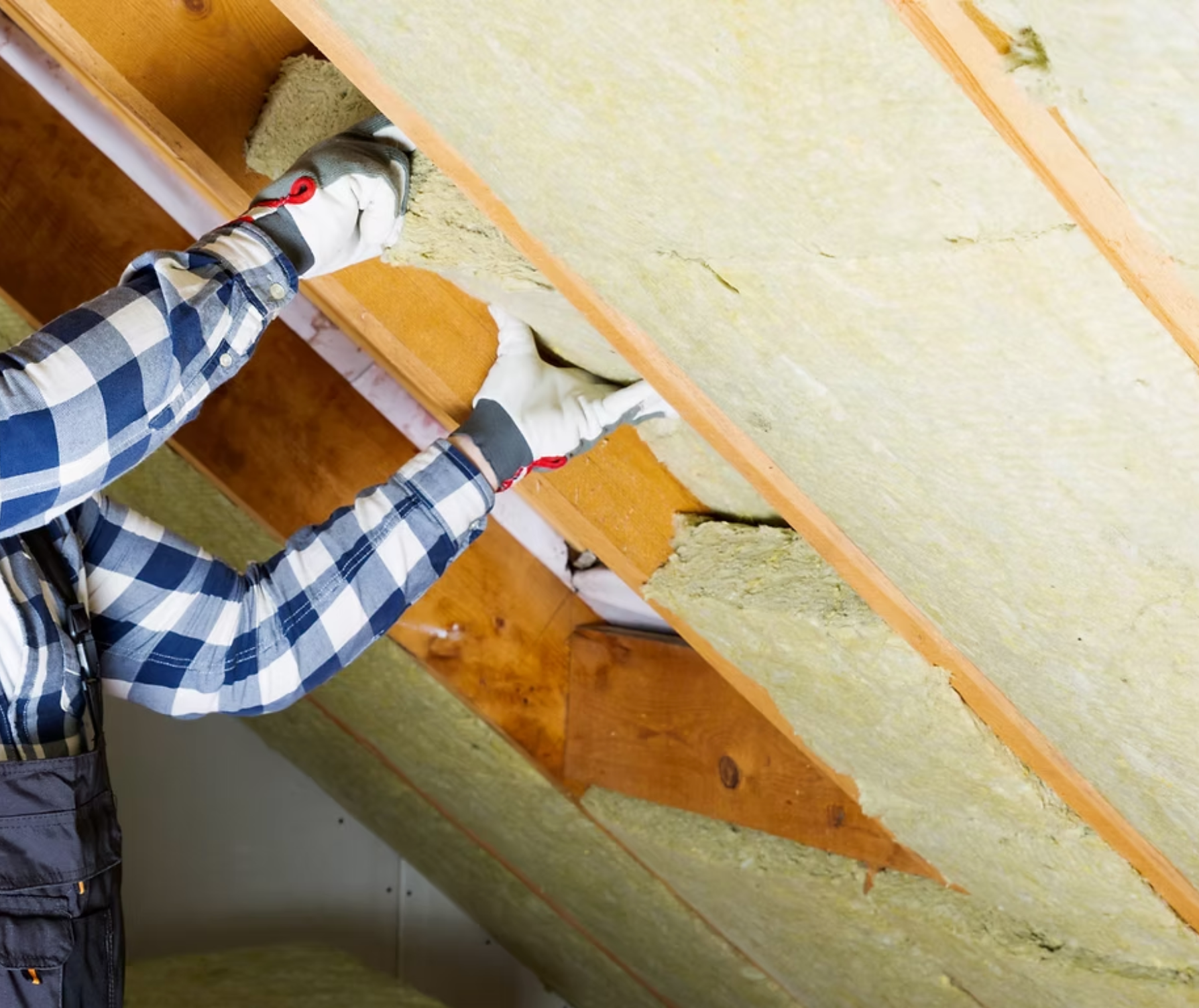 A man is installing insulation on the roof of a house.