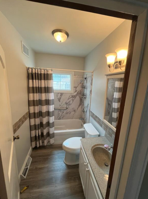 Bathroom with white walls, grey flooring, white and grey striped shower curtain, and a white vanity.