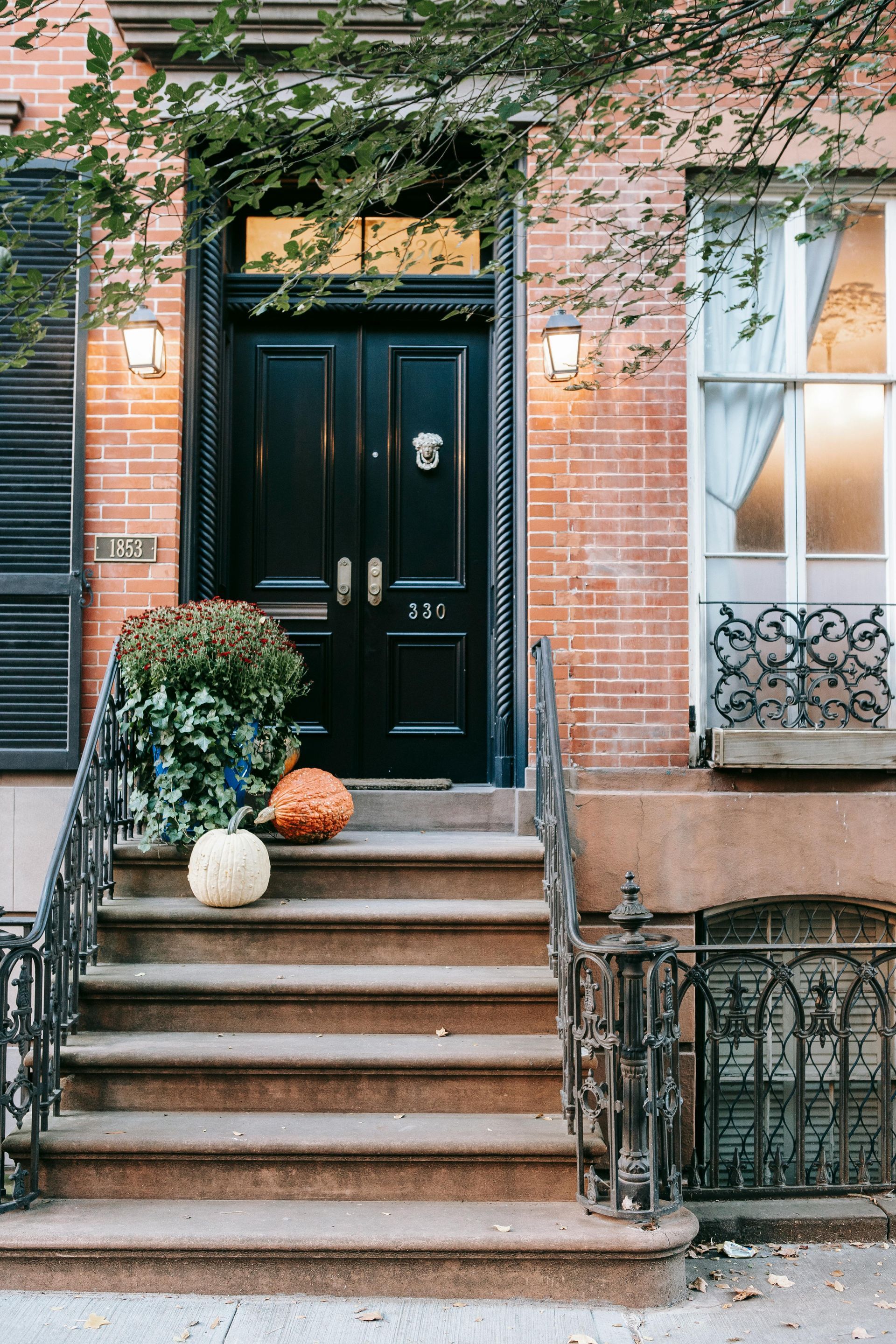 A black door with pumpkins on the steps of a brick building.