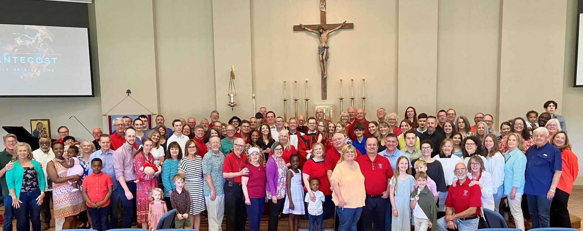 Congregation posing for a picture in front of a cross at Saint Barnabas church.