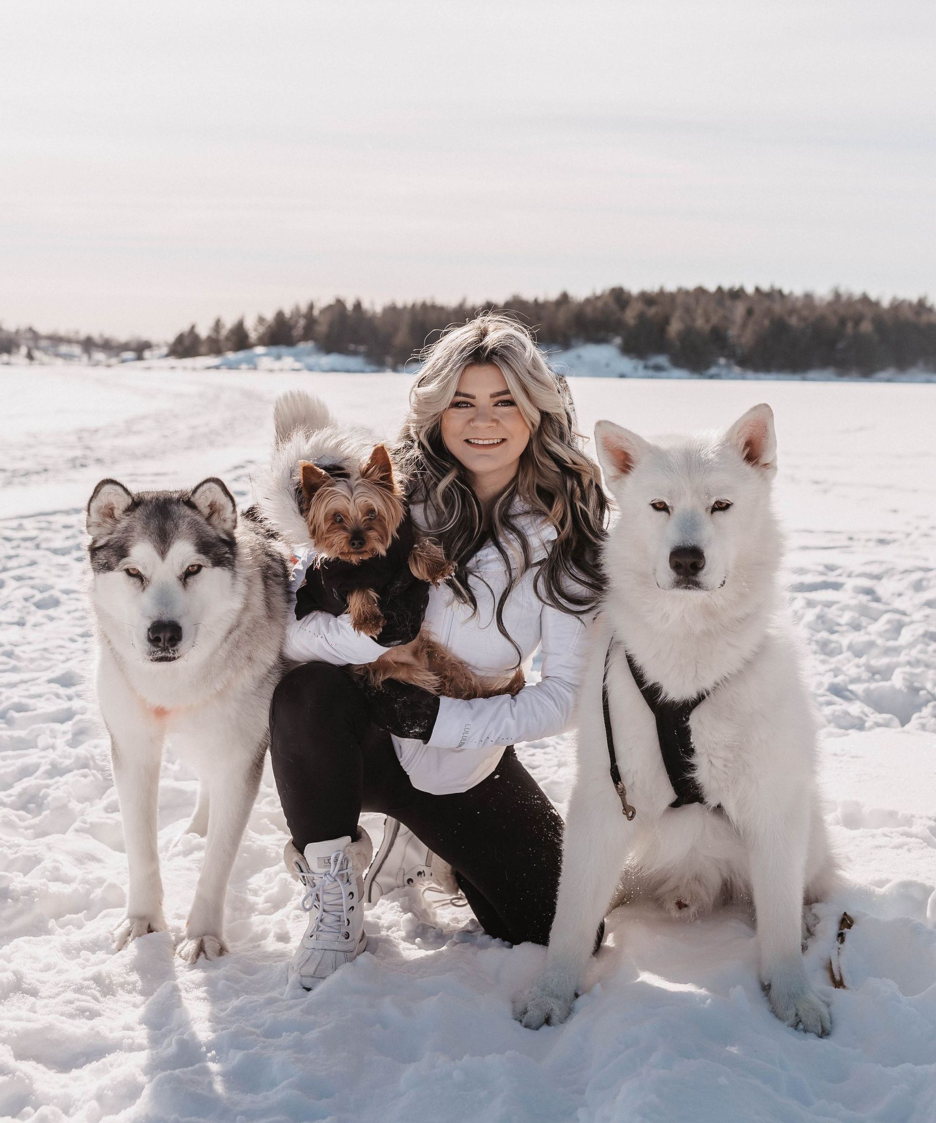A woman in white pants and a white jacket is jumping in the air.