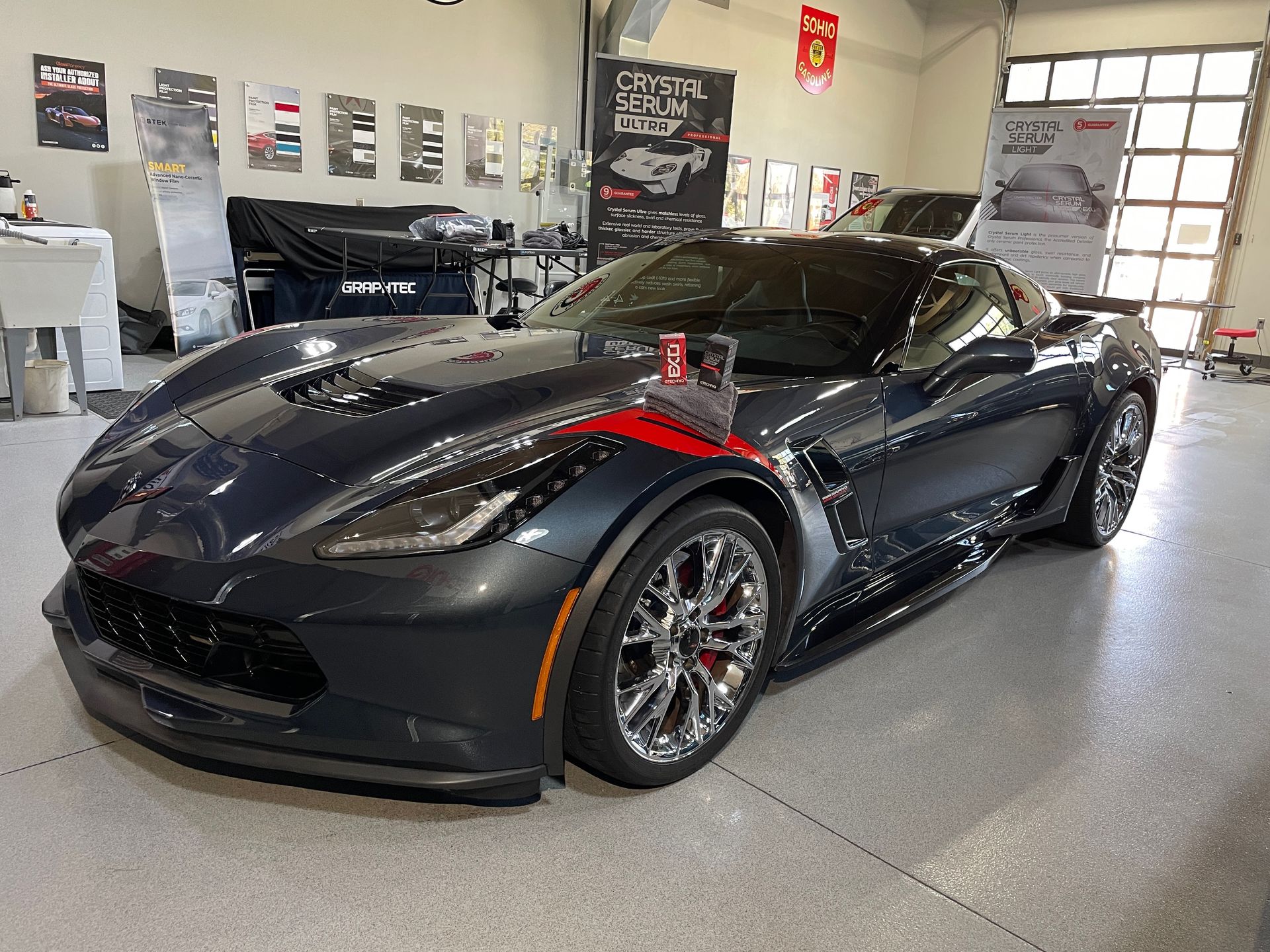 Gray sports car parked inside a garage, with red accents and chrome wheels.