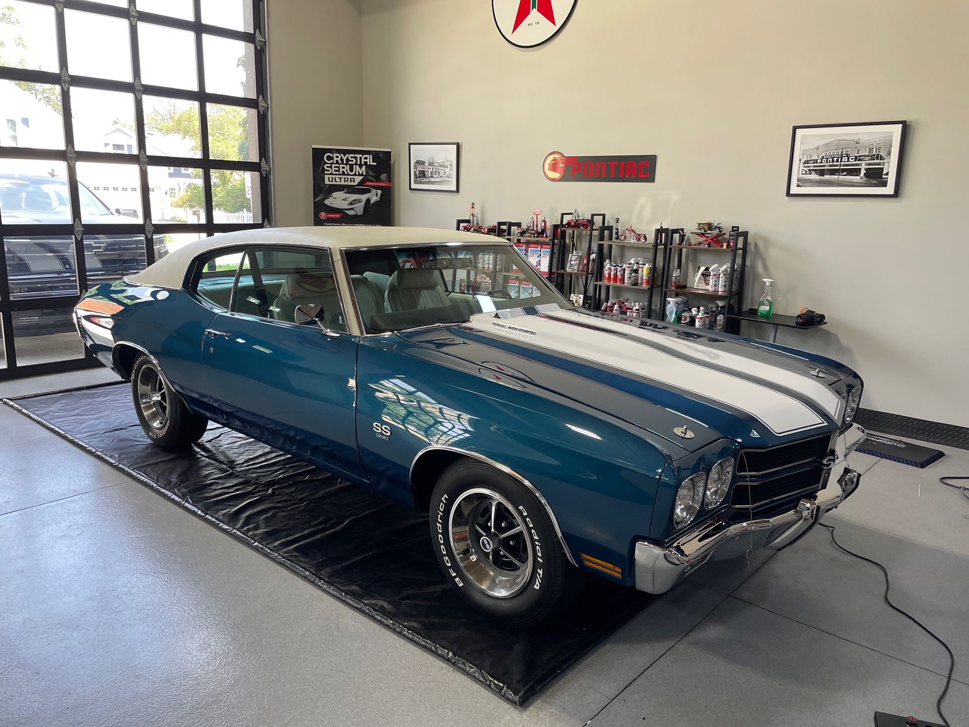 Blue classic car with white racing stripes in a garage.