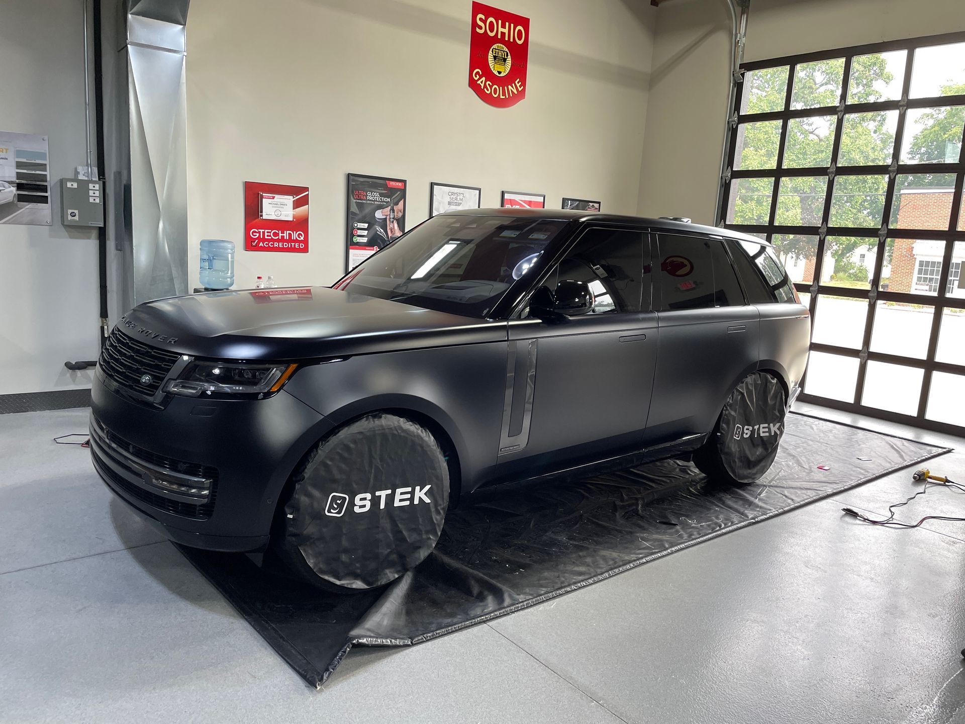 Black SUV parked inside a garage. The vehicle has tinted windows and covers on the wheels.