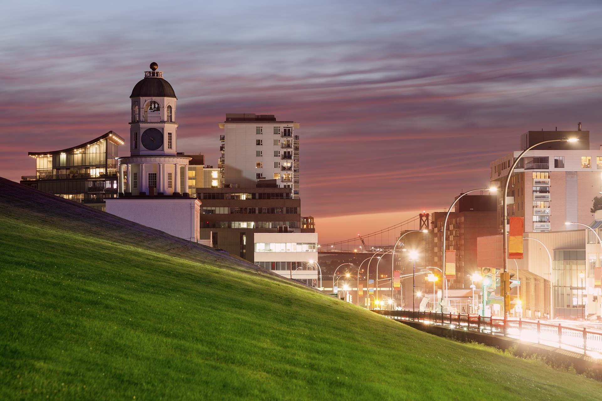 A city at night with a clock tower in the foreground.