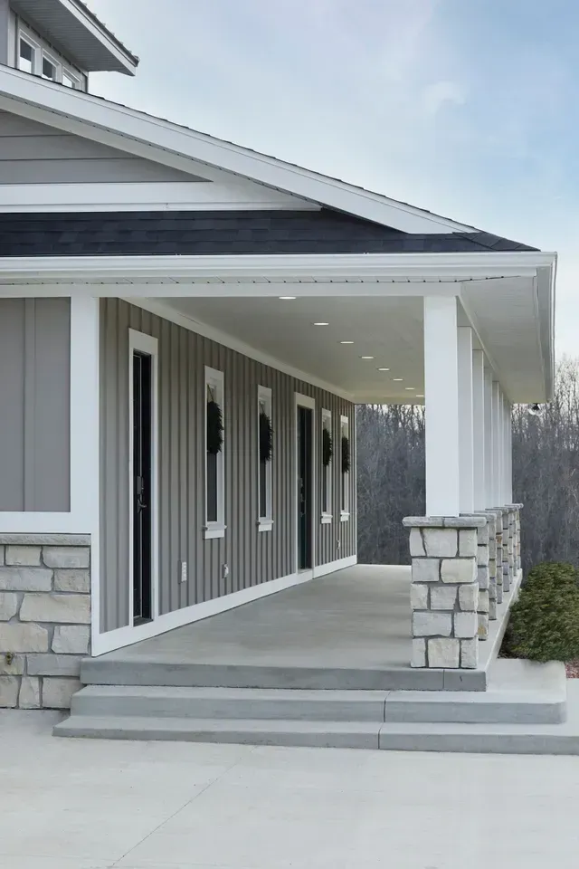 Gray and white house with a covered porch featuring stone columns and steps.