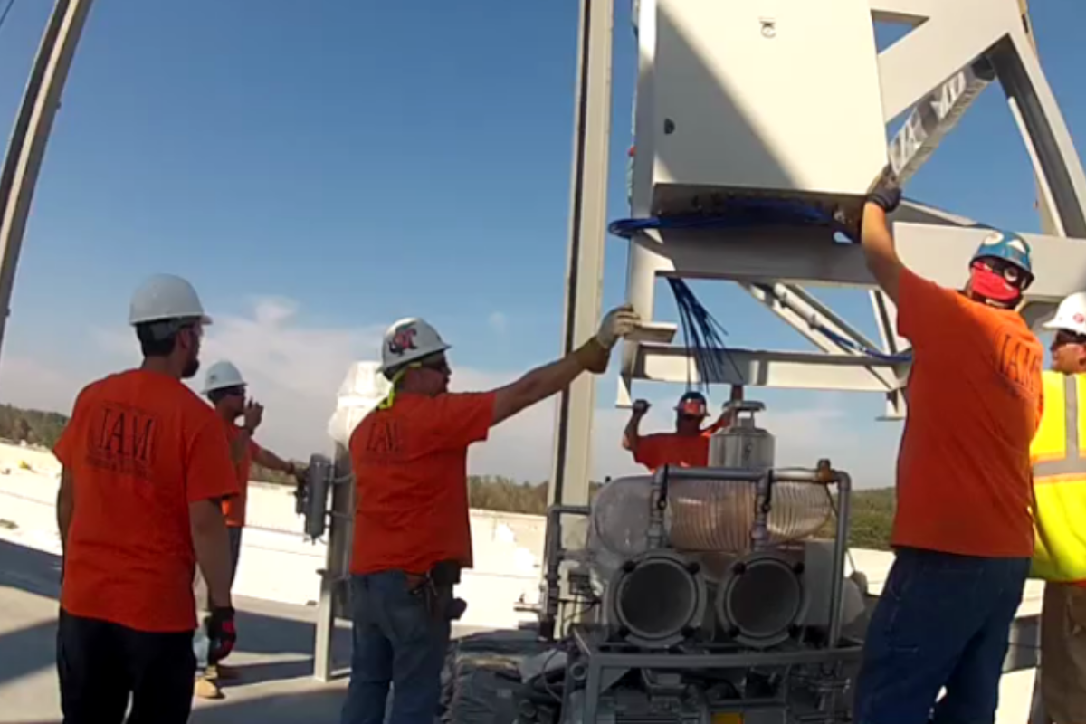 A group of construction workers wearing orange shirts and hard hats