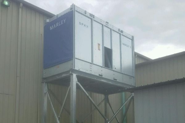 A large container is sitting on top of a metal structure in front of a building.