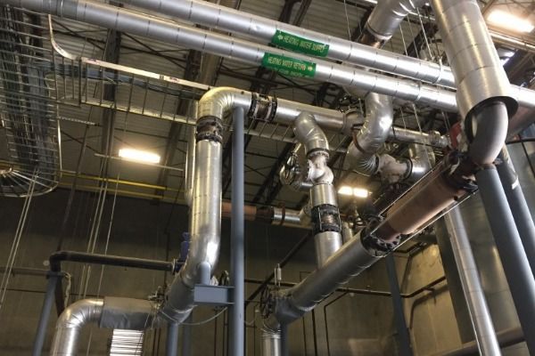 A bunch of pipes are hanging from the ceiling of a building.