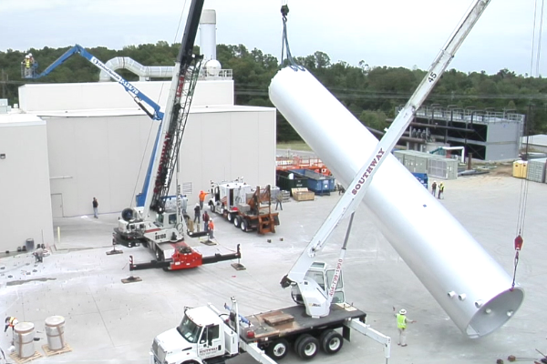 A large white cylinder is being lifted by a crane