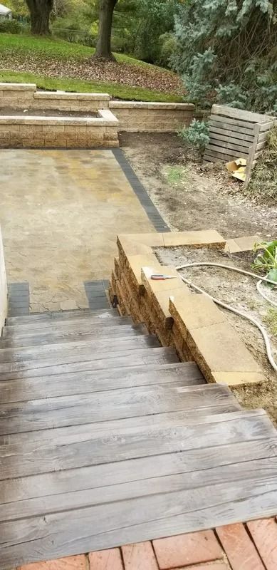 Wooden stairs leading to a concrete path and low retaining walls in a park setting