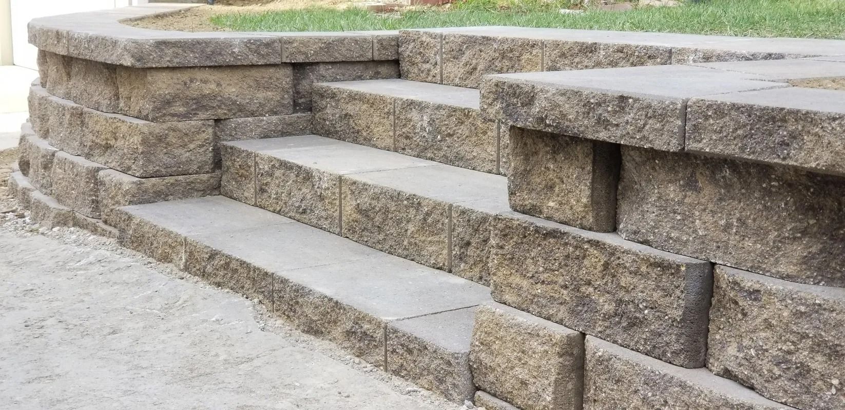 Stone steps and retaining wall leading up a grassy slope outdoors