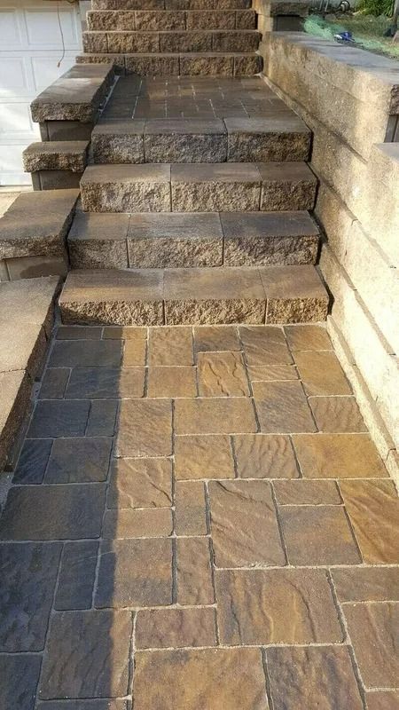 Stone steps leading up from a brick-paved walkway between low stone walls