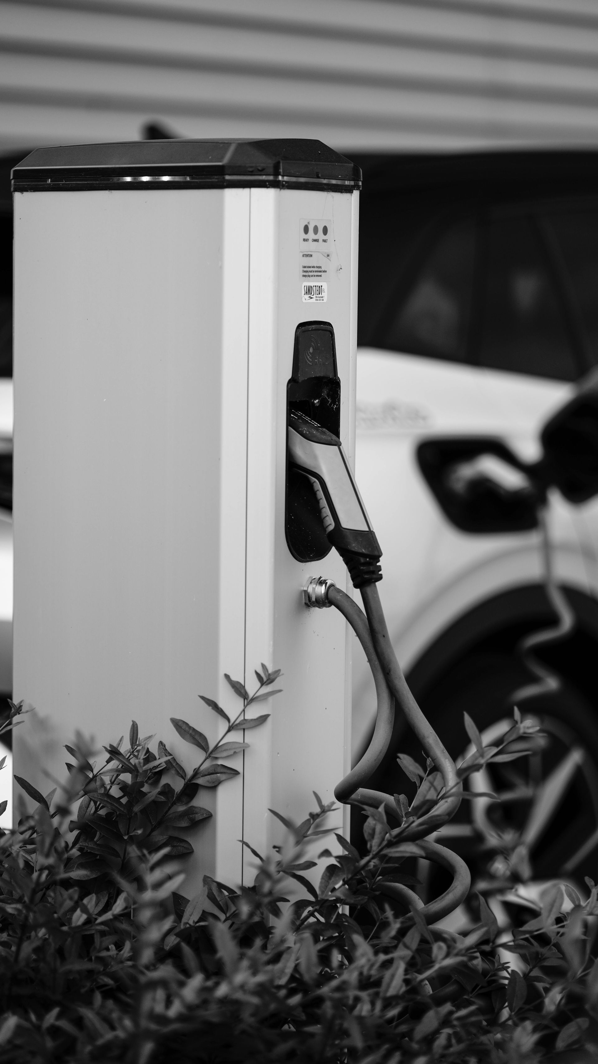 A white electric car is being charged at a charging station.