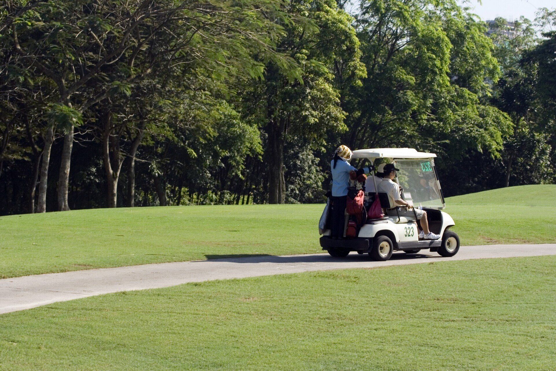People in golf cart traveling around course - Wendell, NC - Champ's Paving & Seal Coating INC