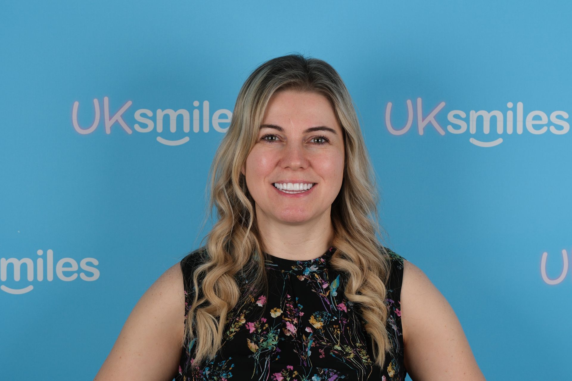 Woman smiling in front of a blue background with