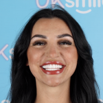 Woman with dark hair and large, white teeth smiles at the camera.