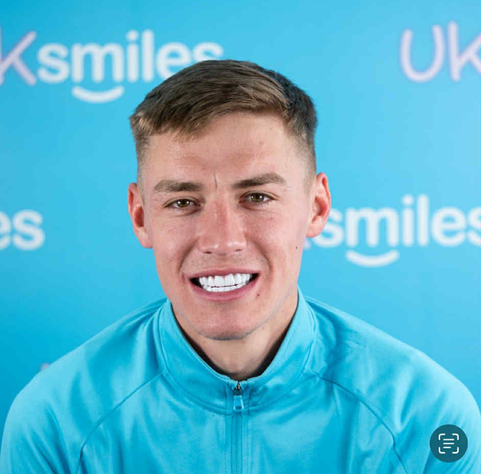 Man smiling broadly, blue background with “UKsmiles” logo.