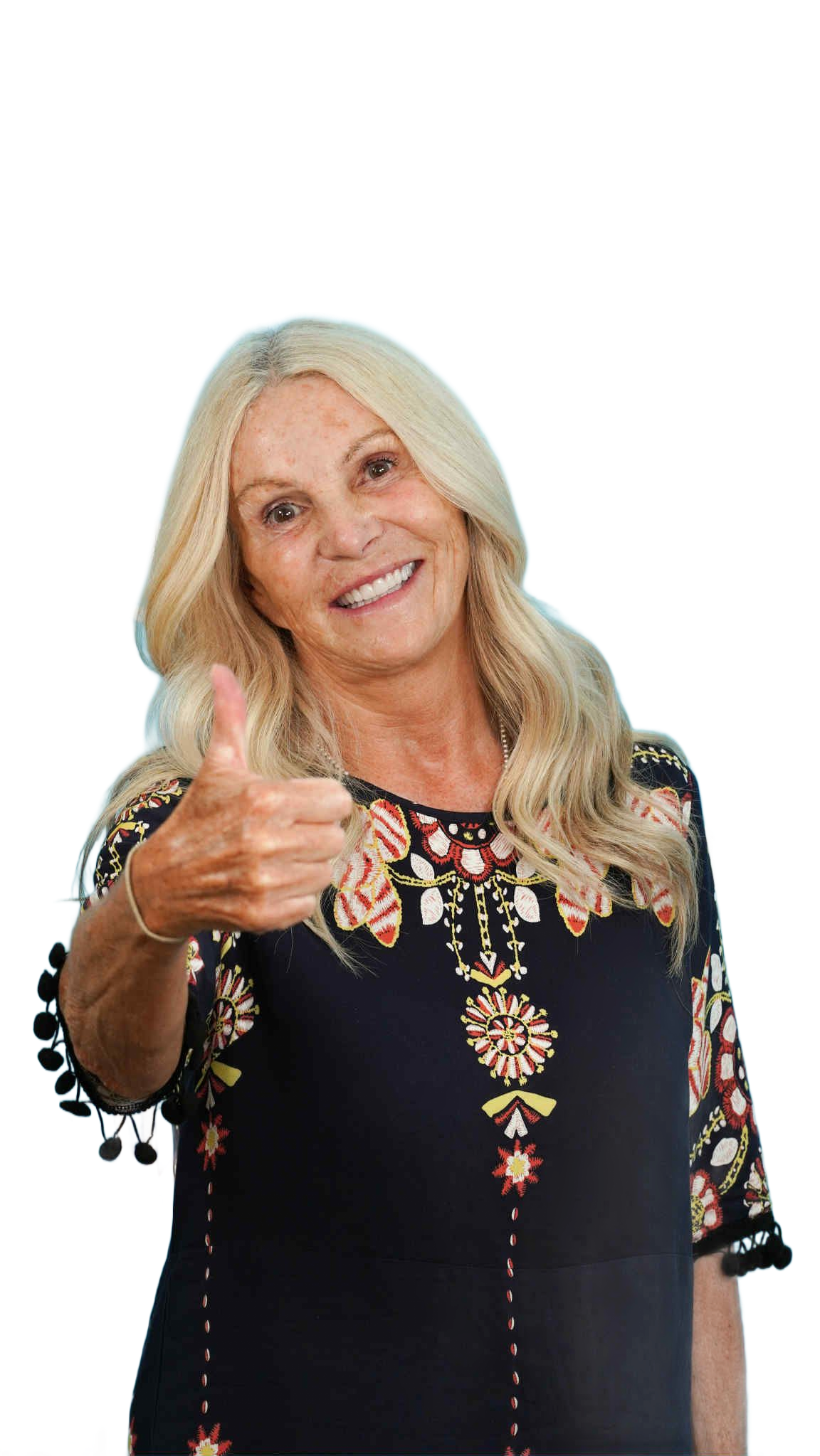 Woman with blonde hair smiling, giving a thumbs up. She wears a dark top with floral design.
