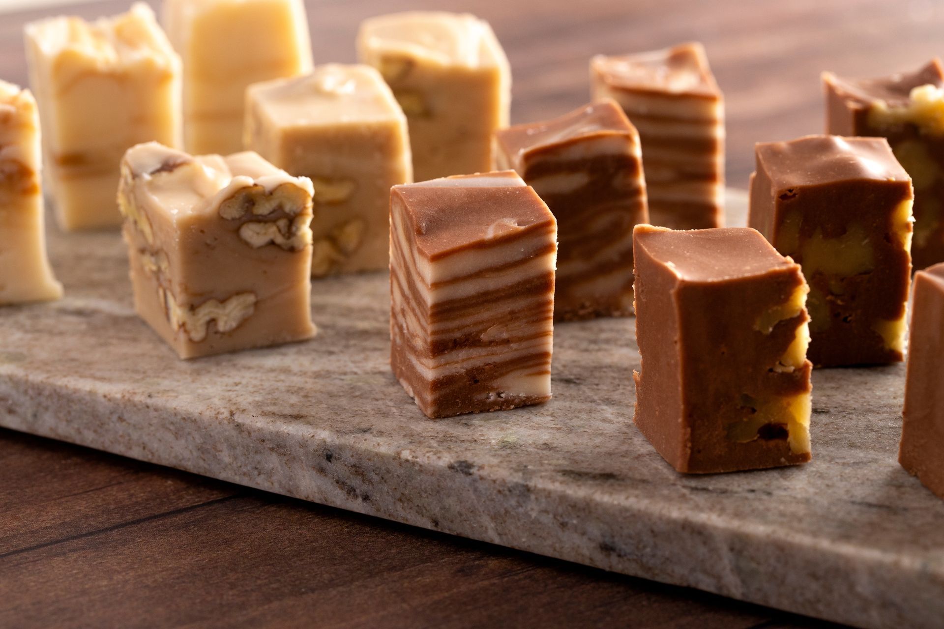 Assortment of fudge pieces on a marble surface. Fudge varieties include layers and nuts.