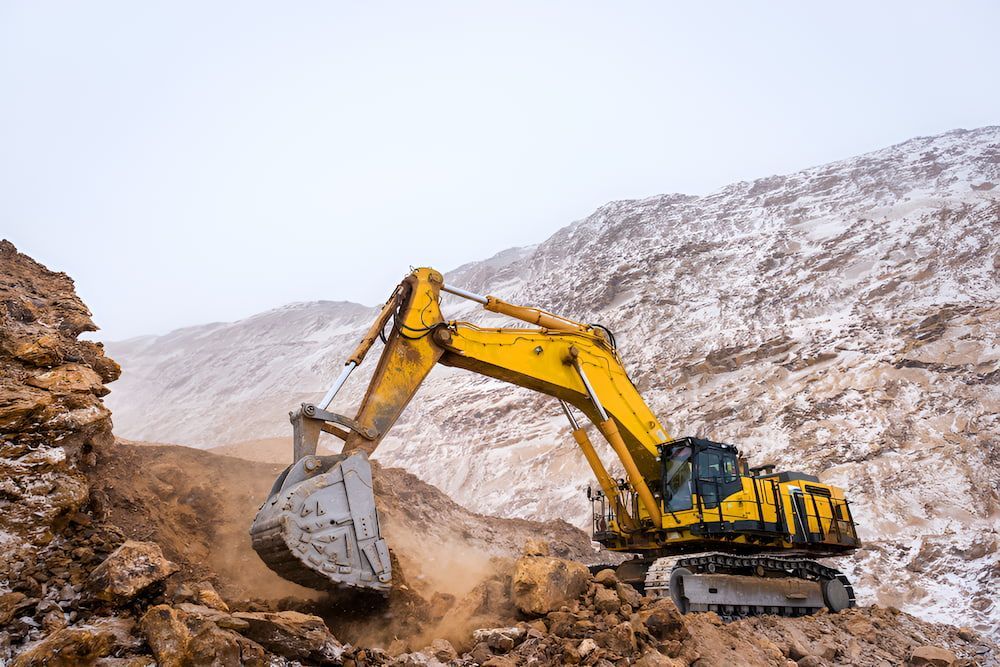A Yellow Excavator Is Moving Dirt In A Mountainous Area — Macquarie Valley Rock & Sand In Wellington, NSW