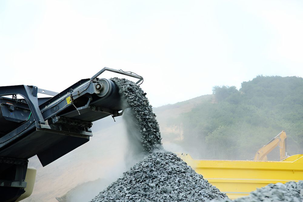 A Pile Of Gravel Is Being Poured Into A Yellow Dumpster — Macquarie Valley Rock & Sand In Mudgee, NSW