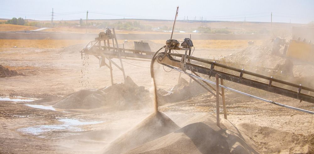 A Conveyor Belt Is Carrying Sand In A Dirt Field — Macquarie Valley Rock & Sand In Mudgee, NSW