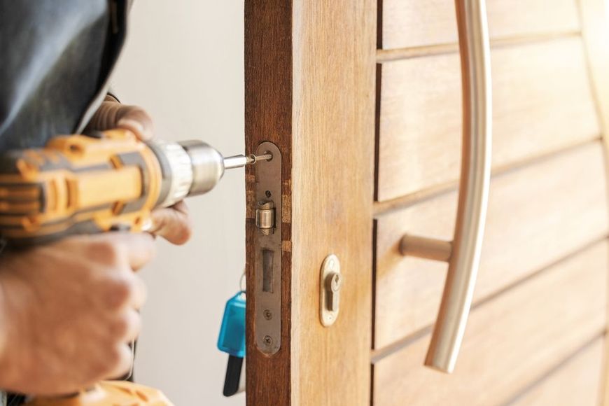 A man is fixing a door with a drill.