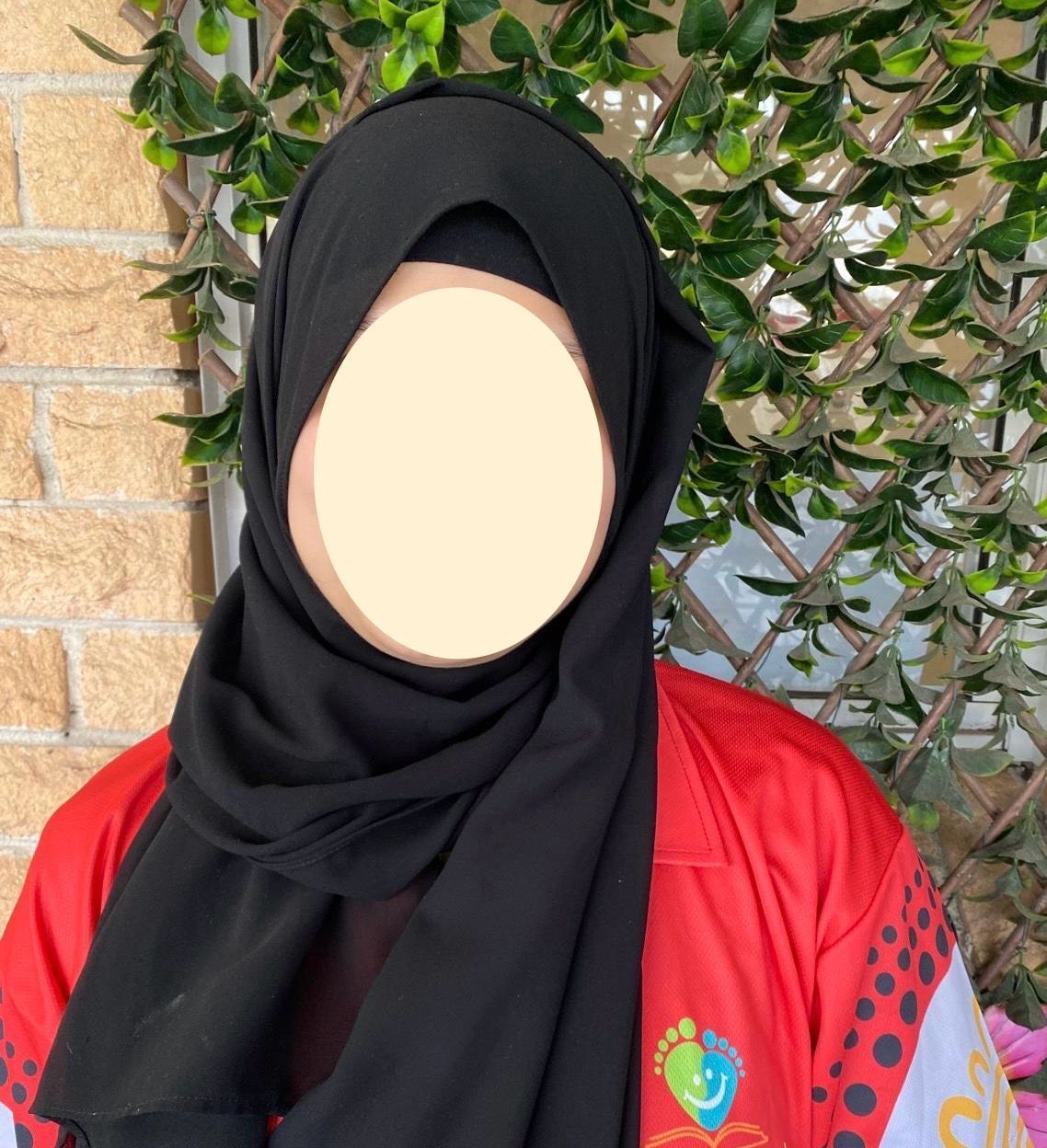 A blurry picture of a woman wearing a blue sweater and a black shirt.