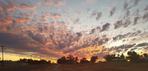 Sunset over a rural landscape with vibrant orange and purple clouds.