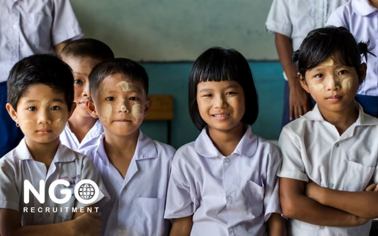 Children in school uniforms, faces with thanaka paste, looking towards the camera.