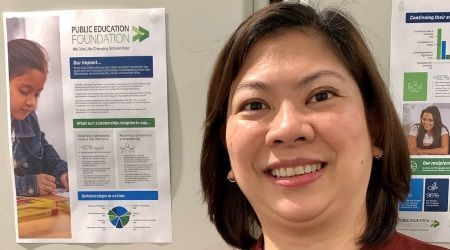 Woman smiling in front of a poster with text and images, including a child.