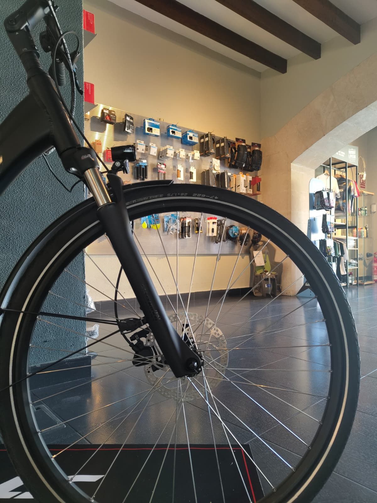 Roda davantera d'una bicicleta negra amb radis platejats, en una botiga.