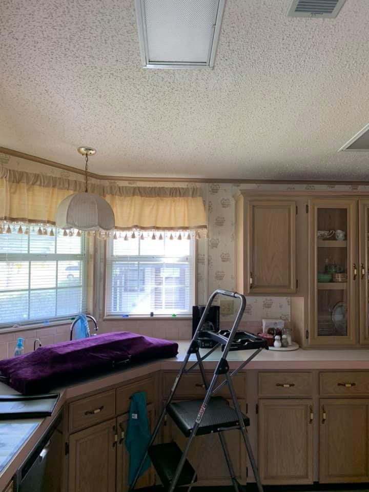 Kitchen interior with cabinets, windows, and a step stool.