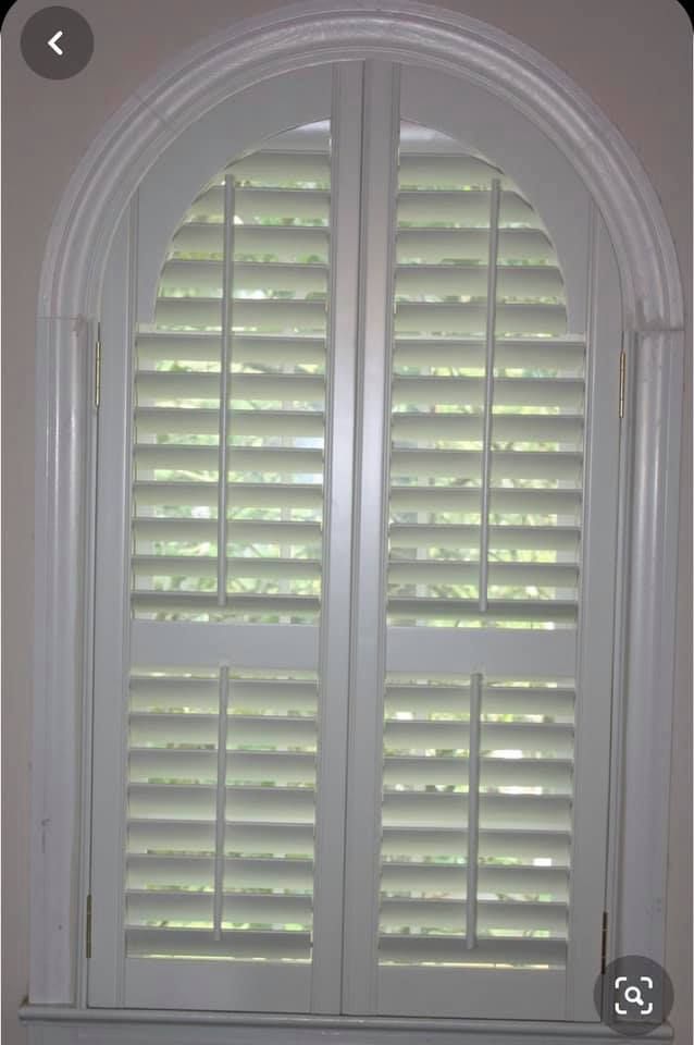 White arched window with closed shutters.