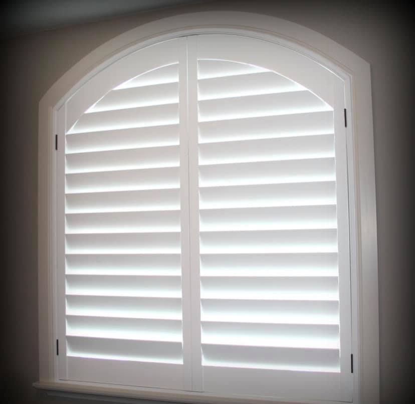 White arched window with closed shutters.