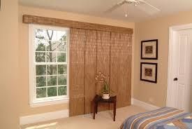 Bedroom with window, bamboo blinds, small table, and bed. Beige walls, white window frame.