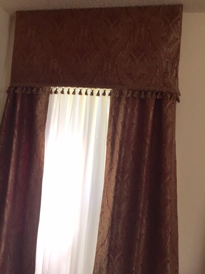 Brown patterned curtains and valance over a window with sheer white curtains.