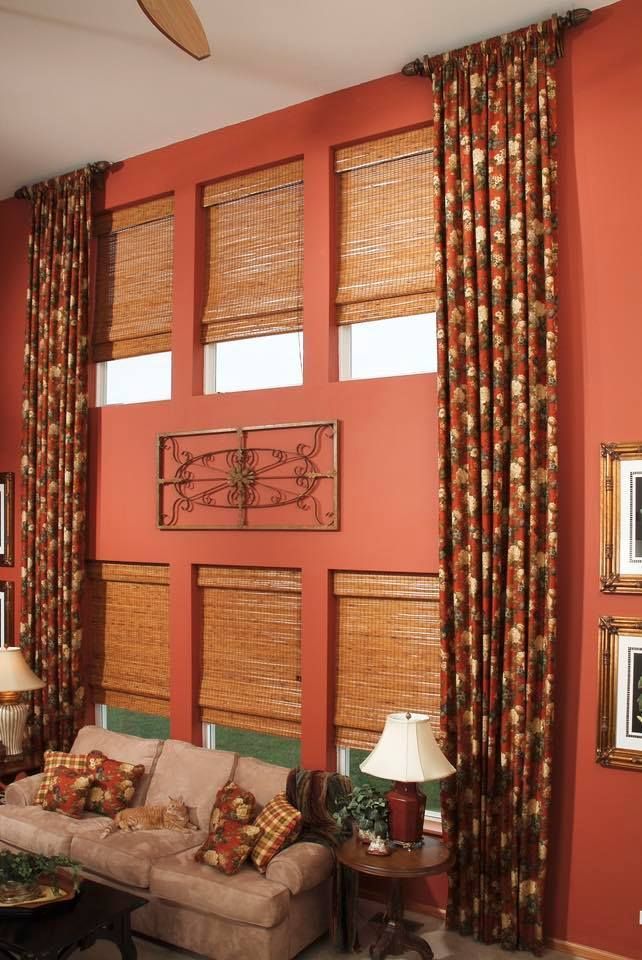 Living room with red walls, windows with bamboo shades, patterned curtains, and a sofa.