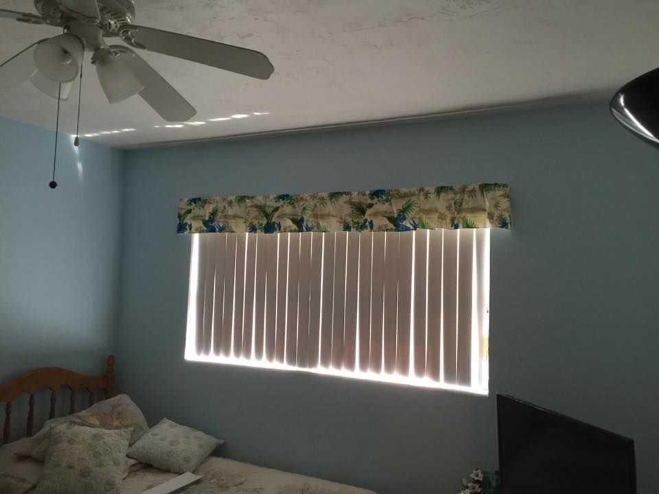 Bedroom with blue walls, window with vertical blinds, and a decorative valance.