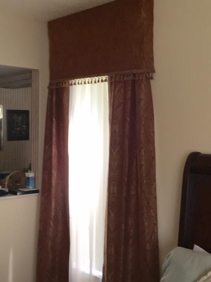 Brown patterned curtains and valance frame a bright window.