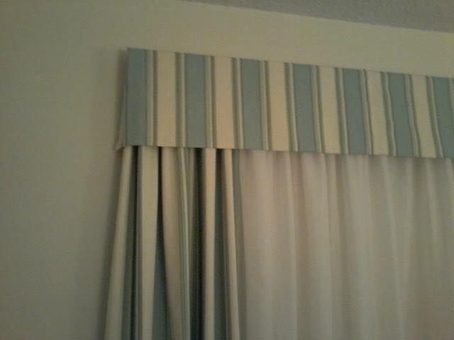 Striped blue and white fabric valance above white curtains.