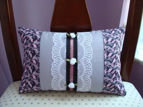 Pillow with floral fabric sides, gray center panel with white lace, pink ribbon and small white buttons.