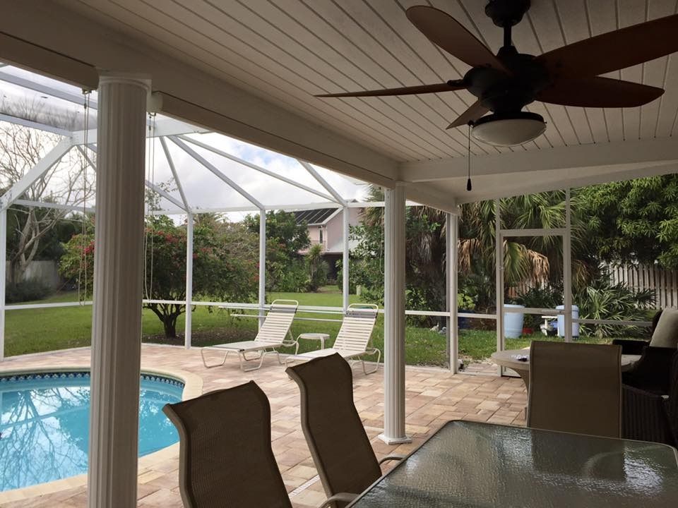 Poolside patio with pool, lounge chairs, dining table, screen enclosure, and ceiling fan.