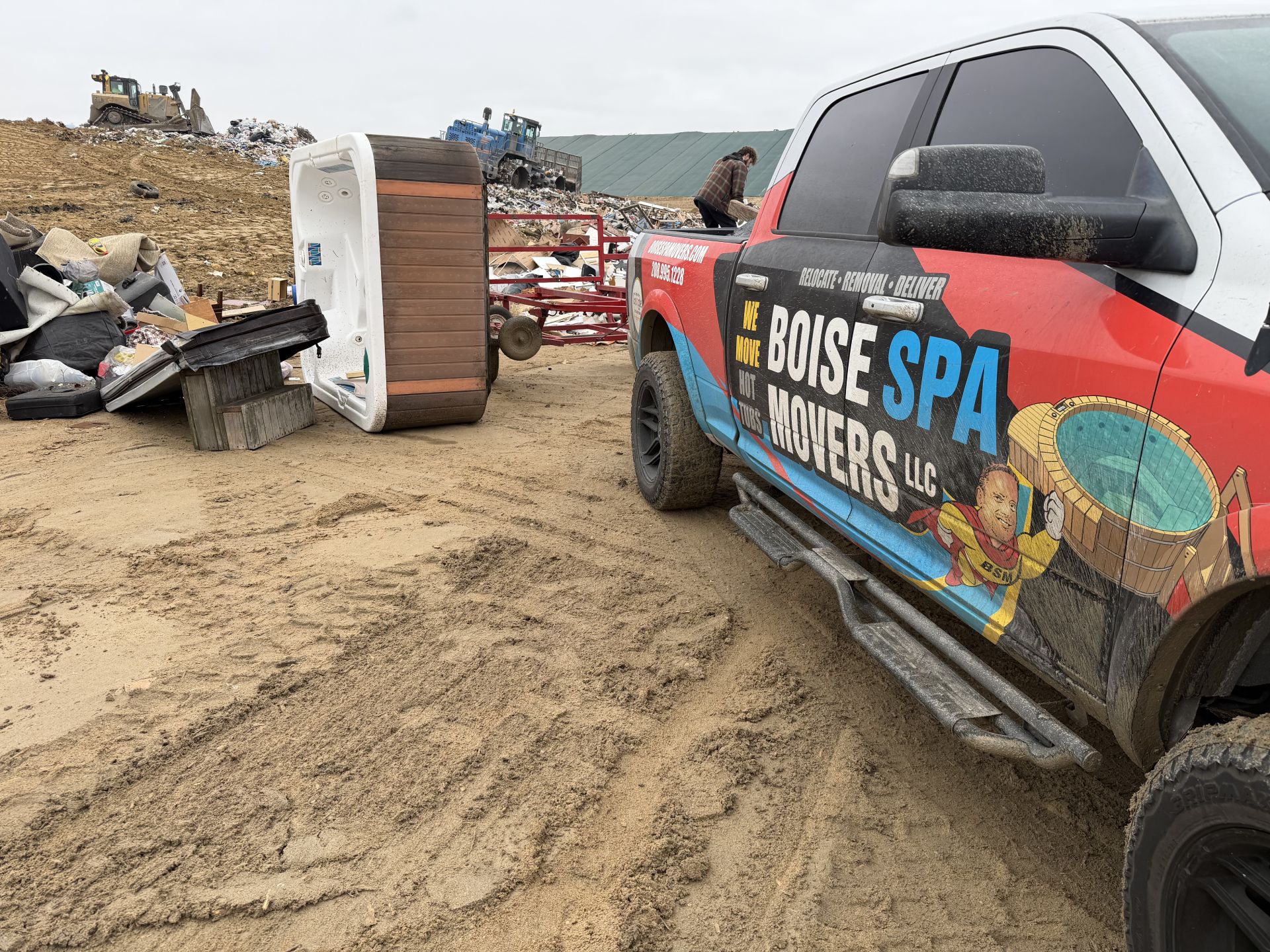 Truck with Boise Spa Miners logo at a landfill, tub in background.